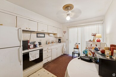 Kitchen with white appliances, light countertops, white cabinetry, and a ceiling fan