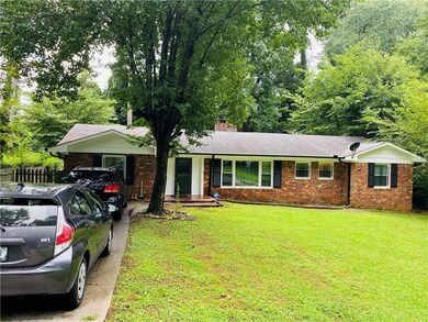 Ranch-style home with a chimney, brick siding, fen