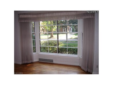 Living room bay window overlooks lovely tree- line