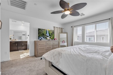 Bedroom featuring light colored carpet, a ceiling fan, and connected bathroom