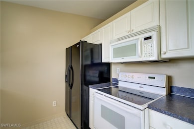 Kitchen with white appliances, dark countertops, w