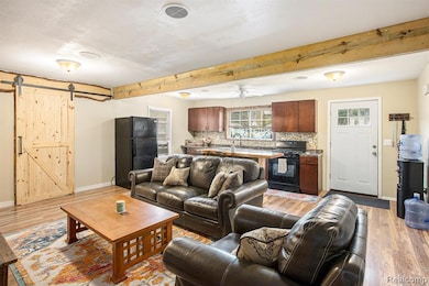 Living room featuring beam ceiling, a barn door, and light wood-style flooring