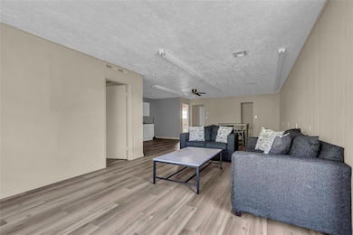 Living area with baseboards, a textured ceiling, v