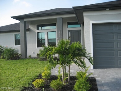 View of exterior entry with a yard and a garage