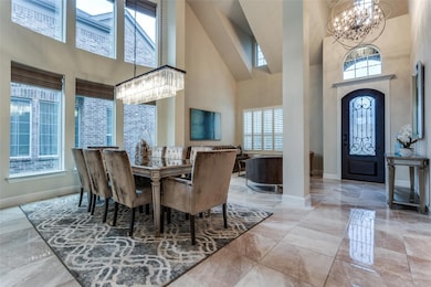 Tiled dining room with a healthy amount of sunlight, an inviting chandelier, and a towering ceiling