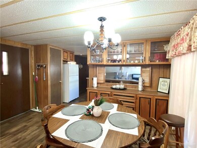 Dining room with a chandelier, wooden walls, and dark wood-style flooring