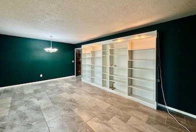 Empty room featuring a textured ceiling and a chandelier