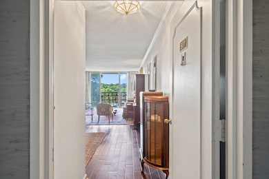 Hall featuring a textured ceiling, wood finished floors, and crown molding