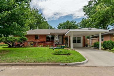 Single story home featuring brick siding, concrete driveway, and a carport