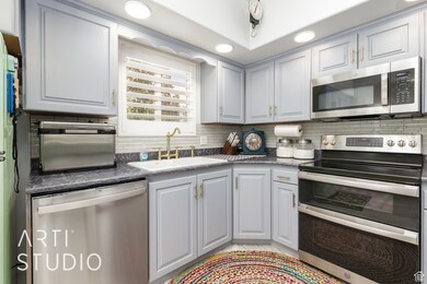 Kitchen featuring stainless steel appliances, backsplash, and dark countertops