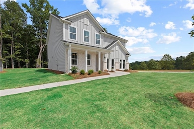 View of front of home with board and batten siding, a front lawn, and brick siding