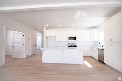 Large kitchen adjoining den/office with quartz slab countertops, painted white cabinets, gas range and other appliances.