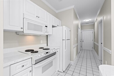 Kitchen with white cabinetry, white appliances, li