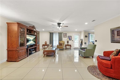 Living area featuring crown molding, light tile patterned floors, ceiling fan, and recessed lighting