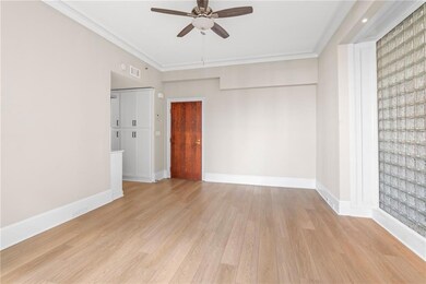 Spare room with a ceiling fan, light wood-style flooring, and ornamental molding