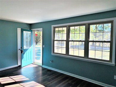 The living room has a glass storm door and three windows to welcome the natural light in.