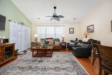 Living area featuring wood finished floors, ceiling fan, and lofted ceiling