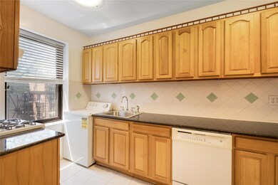 Kitchen featuring white dishwasher, washer / dryer, decorative backsplash, and light tile patterned floors