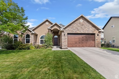 View of front facade featuring a front yard, concrete driveway, an attached garage, and stone siding