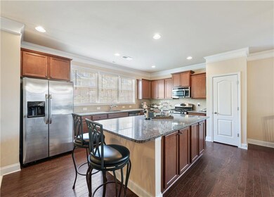 Kitchen with appliances with stainless steel finishes, dark stone countertops, dark wood-type flooring, a center island, and crown molding
