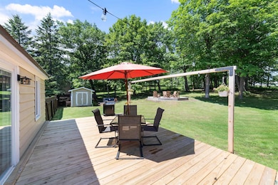 Wooden deck with a storage unit, outdoor dining area, area for grilling, an outdoor fire pit, and a fenced backyard