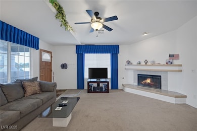 Carpeted living area with a ceiling fan and a tile