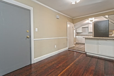 Wide plank floors in dining area that leads up short step to remodeled kitchen