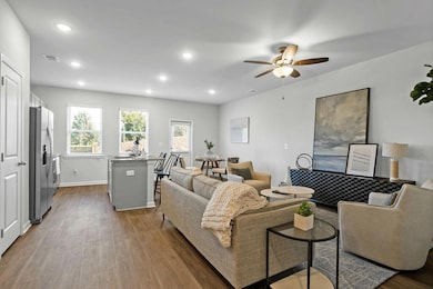 Living room featuring ceiling fan and dark wood-type flooring