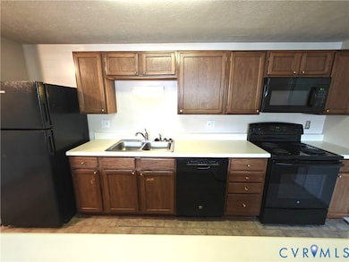 Kitchen featuring black appliances, light countertops, and a textured ceiling