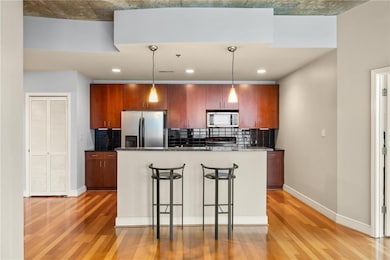 Kitchen with stainless steel appliances, light wood-type flooring, a kitchen bar, backsplash, and recessed lighting