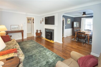 Living room with a tiled fireplace, dark wood-type flooring, and ceiling fan