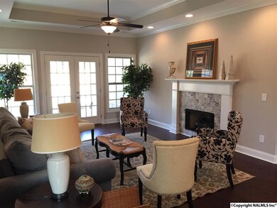 Living room has fireplace, trey ceiling, hardwood floors and french doors leading to covered patio.