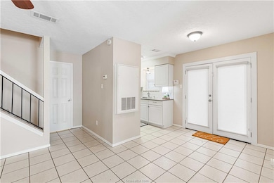 Kitchen featuring light tile patterned floors, white cabinetry, and a textured ceiling