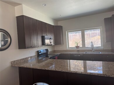 Kitchen with sink, stone countertops, dark brown c