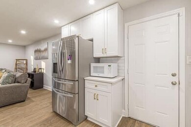 Kitchen with a sink, white cabinets, a center island with sink, light wood-style floors, and recessed lighting