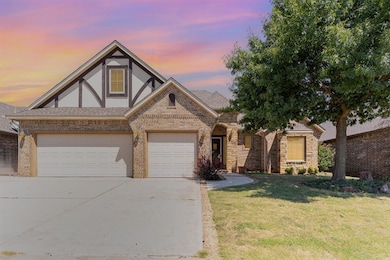 Tudor home with roof with shingles, driveway, brick siding, a garage, and a yard