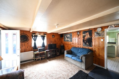 Carpeted living area featuring beamed ceiling, a textured ceiling, and wooden walls