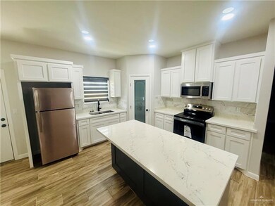Kitchen with white cabinetry, appliances with stainless steel finishes, light wood-style floors, a kitchen island, and tasteful backsplash