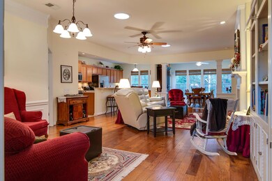 Living room with hardwood floors, fireplace with marble hearth, solar tubs for natural light and ceiling fan. 