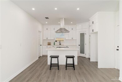 Kitchen featuring island range hood, light wood finished floors, a kitchen island, light countertops, and recessed lighting
