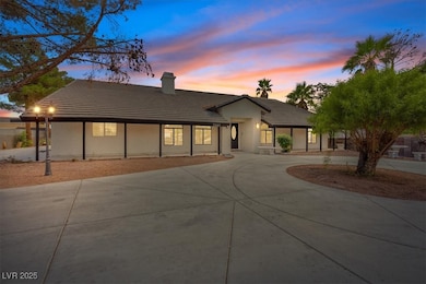 Ranch-style house with a tiled roof, curved driveway, a chimney, and stucco siding