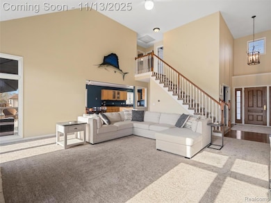 Living area featuring high vaulted ceiling, healthy amount of natural light, carpet floors, and stairs