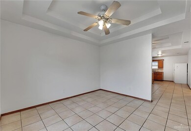 Unfurnished room featuring ceiling fan, a tray ceiling, and light tile floors