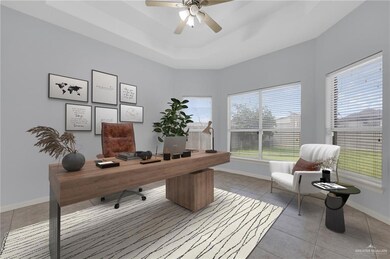 Office space featuring a ceiling fan, light tile patterned floors, and a raised ceiling