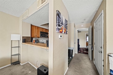 Corridor with light carpet and a textured ceiling