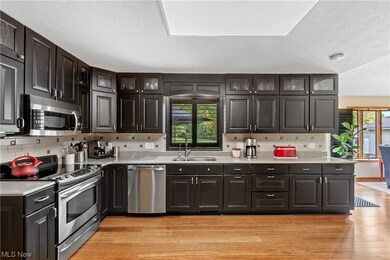 Kitchen with light wood-type flooring, tasteful backsplash, sink, and appliances with stainless steel finishes