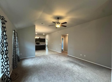 Unfurnished living room with light colored carpet, a chandelier, lofted ceiling, and ceiling fan