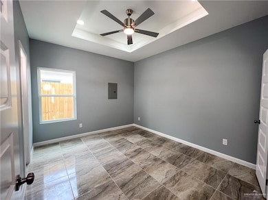 Unfurnished room with a raised ceiling, electric panel, and ceiling fan