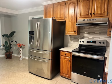 Kitchen with light countertops, appliances with stainless steel finishes, brown cabinets, tasteful backsplash, and ornamental molding
