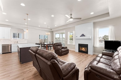 Living area with light wood-style floors, recessed lighting, healthy amount of natural light, a large fireplace, and a raised ceiling